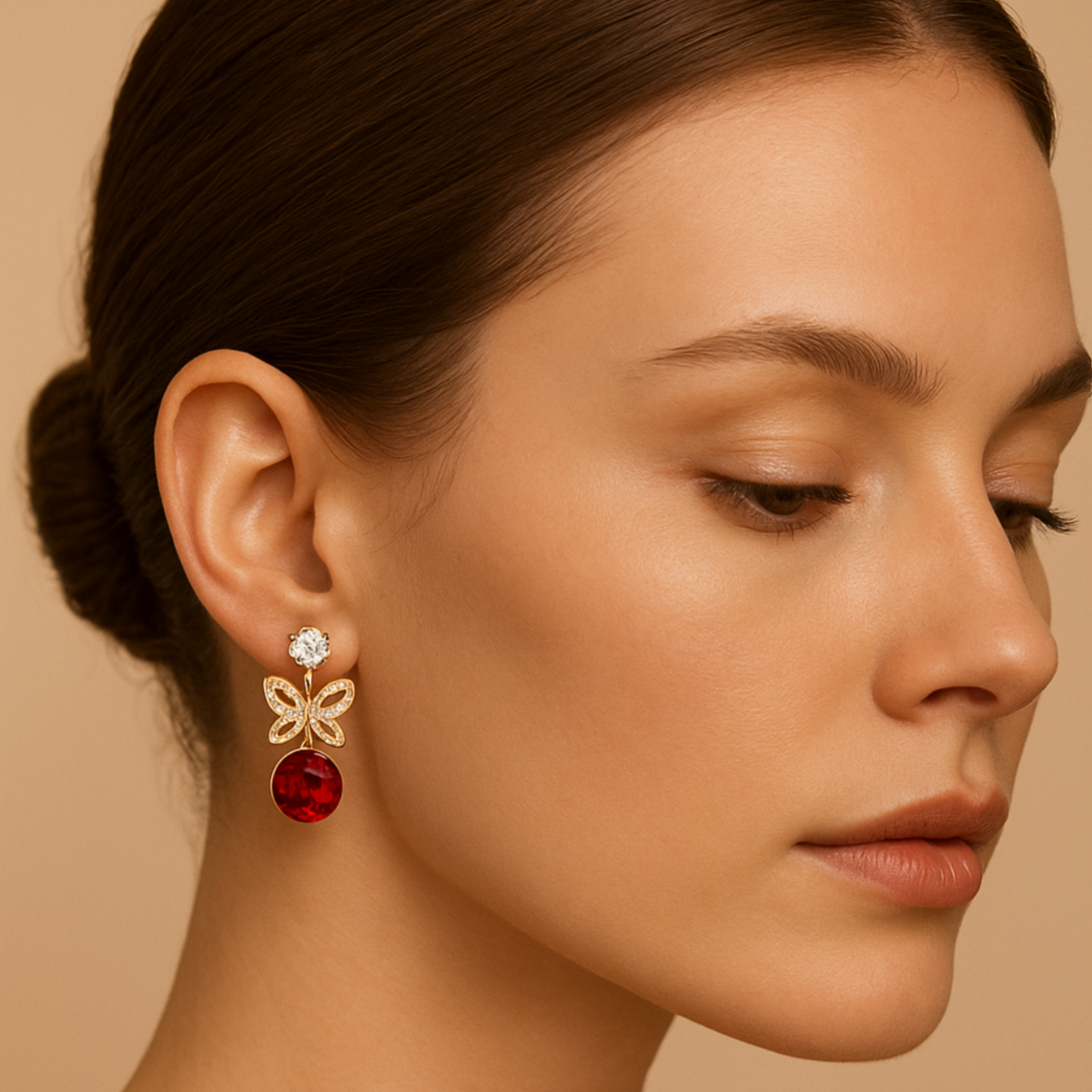 Close-up of a woman wearing a gold earring with a red gemstone on a beige background